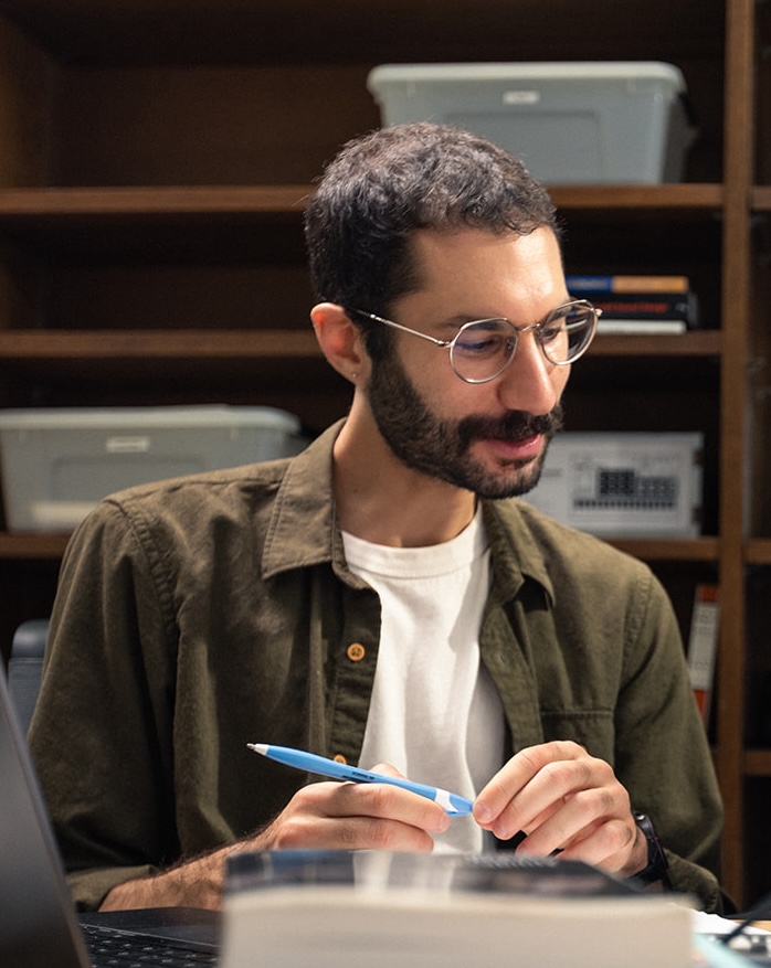 Skinny Jewish dude in his early thirties with short curly hair, and silver, wireframe glasses.